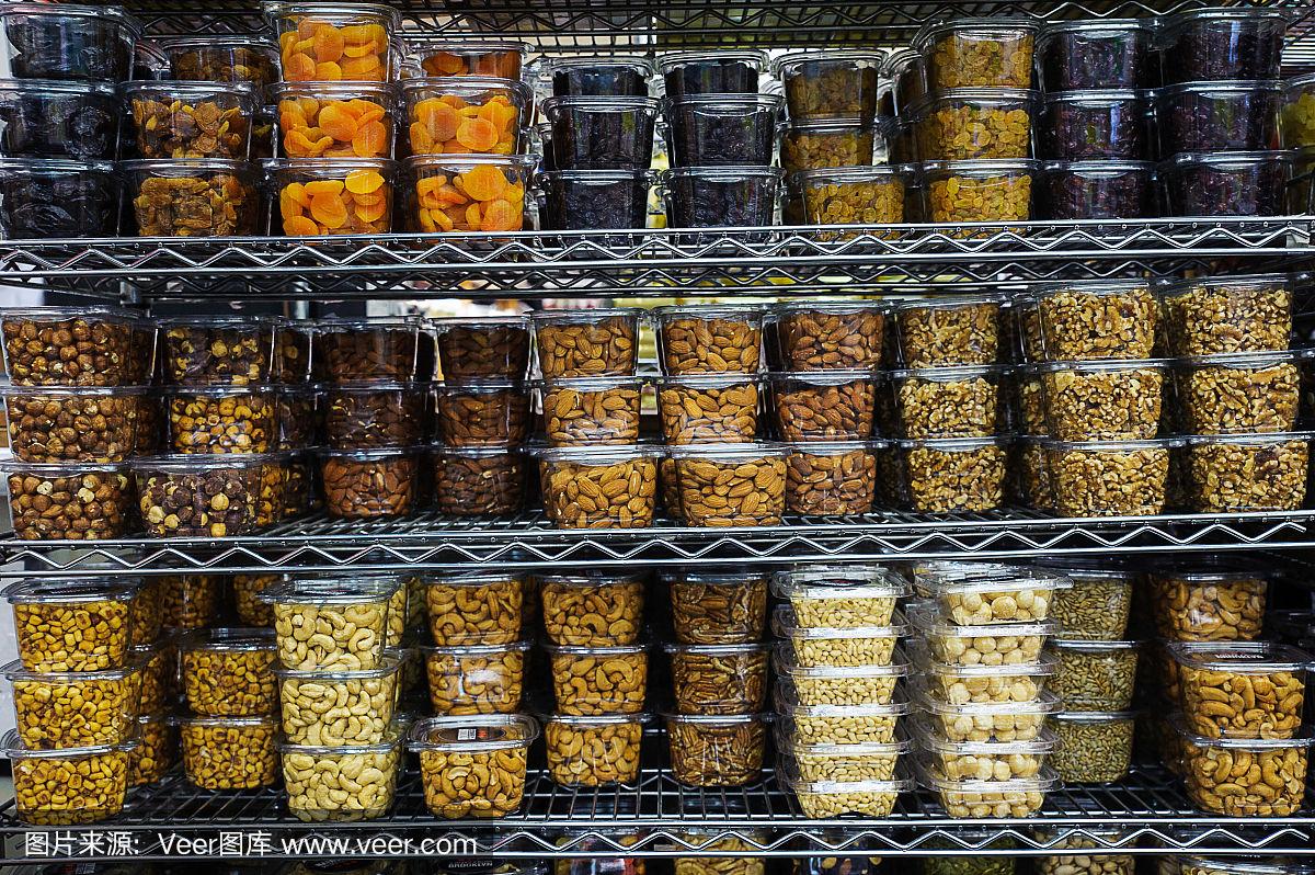 各种干果和坚果装在塑料容器里塞满了超市的金属货架 各种干果和坚果装在塑料容器里塞满了超市的金属货架